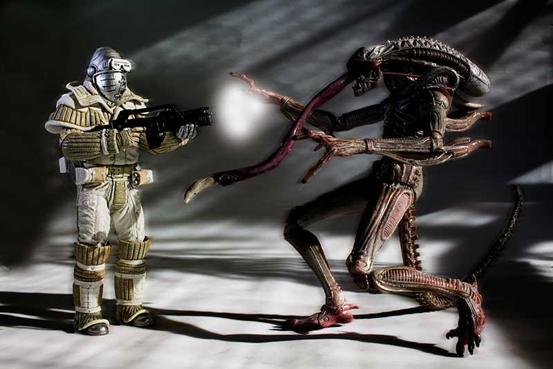 Weyland-Yutani Commando fires weapon against fierce Xenomorph